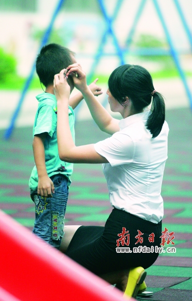 一名老师正在给听力班的孩子佩戴助听器。这里的老师更多时候扮演着家长的角色。